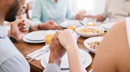 We stay together because we pray together. a beautiful family blessing the food with a prayer at the table together at home.の写真素材