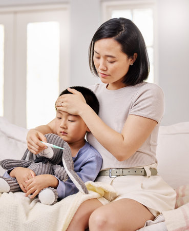 Doesnt look like its coming down. a woman checking her sick childs temperature.の写真素材