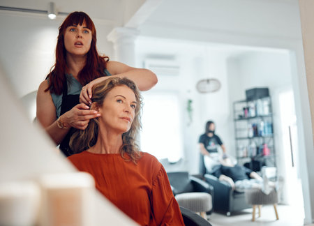 Mirror reflection of senior woman, hairdresser and salon studio employee working on client haircut,...