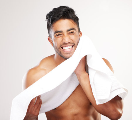 Great days start with a good morning. young man wiping his face with a towel against a grey background.の写真素材