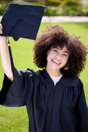 Congrats on your fancy new hat. Portrait of a young woman holding her cap on graduation day.の写真素材
