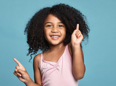 .Children, dance and fun with a girl kid dancing in studio on a blue background for freedom or expression. Kids, happy and smile with a cute female child dancer feeling positive or carefree inside.の写真素材