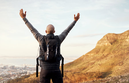 The view from the top. Rearview shot of an unrecognizable young man enjoying the view during his...