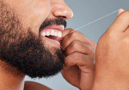 Flossing cleans places that brushing cant. Studio shot of an unrecognizable man using dental floss...