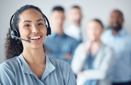 Were committed to giving the best service to all. Portrait of a young call centre agent standing in an office with her colleagues in the background.の写真素材