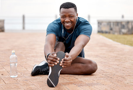 Im wide awake and ready to run this day. Portrait of a sporty young man stretching his legs while exercising outdoors.の写真素材
