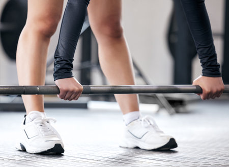 Its between the barbell and me. an unrecognisable woman working out with a barbell in a gym.の写真素材