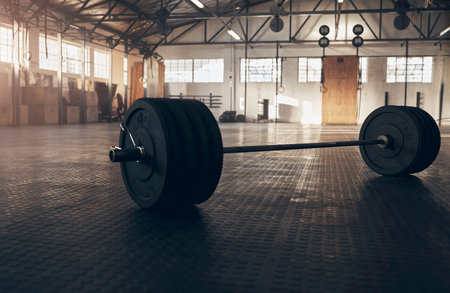 Will you be making muscles or excuses today. Closeup shot of a barbell in an empty gym.