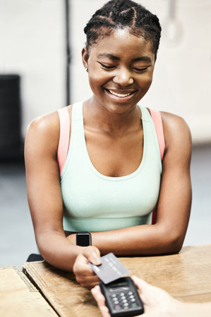 Extending my gym membership. an attractive young woman using her credit card to pay for her gym...