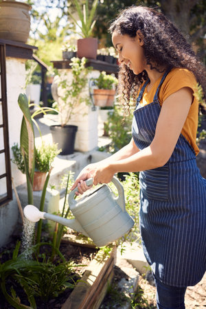 Give them the water they need. a young female florist watering plants at work.の写真素材