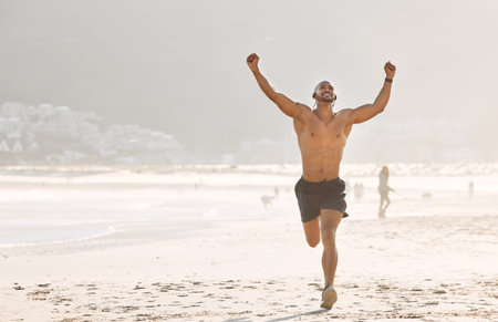 Get comfortable with being uncomfortable. a young man celebrating on the beach.の写真素材