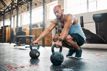 Lift your way to stronger form. a young man getting ready to use kettlebells in his gym.の写真素材