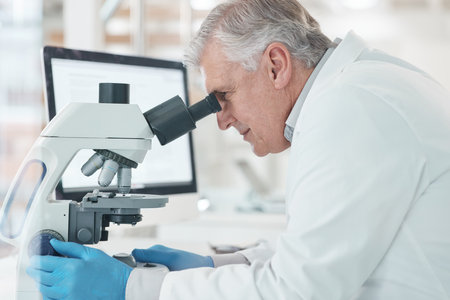 Working towards the precise cure. a mature scientist using a microscope in a lab.の写真素材