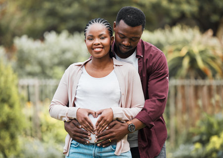 Growing together as a family. a young expecting couple posing together in their yard.の写真素材