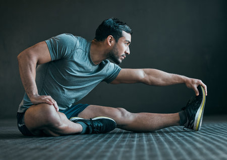 Warming up those muscles. Full length shot of a handsome young male athlete warming up against a...