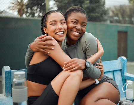 My favourite workout buddy. Cropped portrait of two attractive young female athletes embracing while sitting on a bench outside during their workout.の写真素材