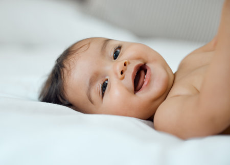 Her giggles are just the cutest. Portrait of an adorable baby girl lying on a bed at home.の写真素材