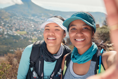 Hiking the trail is a great way to bond. Pprtrait of two young women taking selfies during a hike along the mountain.の写真素材