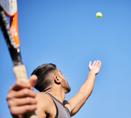 Working on my serve. Low angle shot and unrecognisable man playing tennis outside.の写真素材