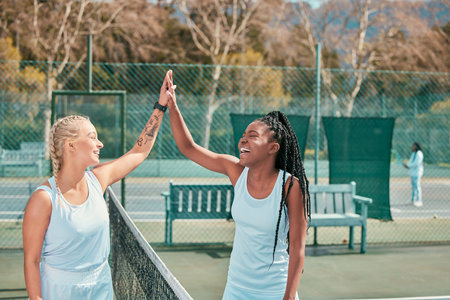 Thats the kind of teamwork Im talking about. a two young women standing and giving each other a high five after tennis practise.の写真素材