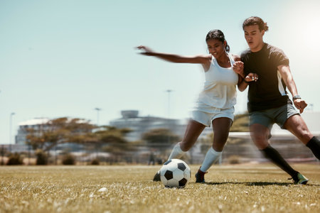 Sport, friends and soccer with man and woman playing on a soccer field, competitive training for sports goal. Fitness, couple and energy with interracial guy and lady having fun with outdoor footballの写真素材