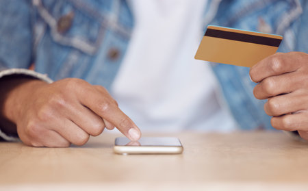 Living in the digital age of convenience. a man using his smartphone to make online card payments.の写真素材