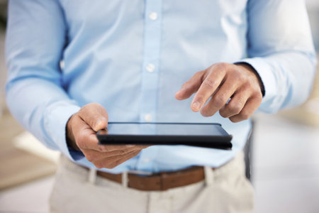 Sending off important documents. a businessman using his digital tablet.の写真素材