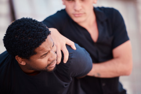 Police, arrest and black man for crime, protest or resistance in street for law, justice and order. Security, city and catch criminal, robber or thief on road outdoor for violence, stealing or theftの写真素材