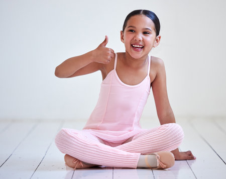 Ballet is awesome. a little girl showing thumbs up in a ballet studio.の写真素材