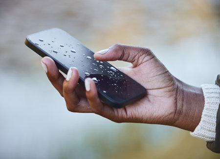 Water damage is so costly to repair. a woman holding a wet phone during a camping trip.の写真素材