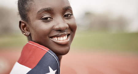 Being an athlete takes dedication. a beautiful young female athlete with the american flag wrapped around herself.の写真素材