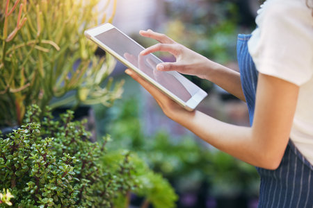 Making my business life easier. a nursery owner using her digital tablet.