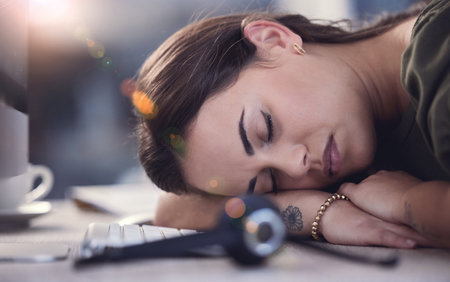 Just need to get my energy up. a young female call center agent taking a nap at work.の写真素材