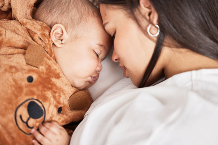 Youre my sweetest gift. a young mother snuggling with her baby boy as he sleeps.の写真素材