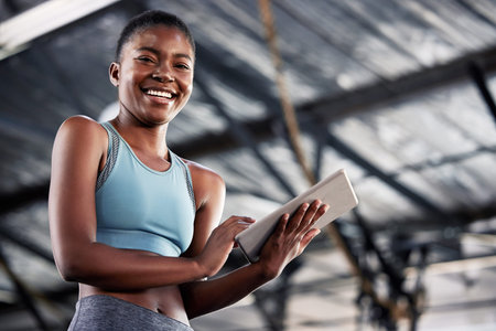 A bad day can be made better at the gym. a sporty young woman using a digital tablet at the gym.