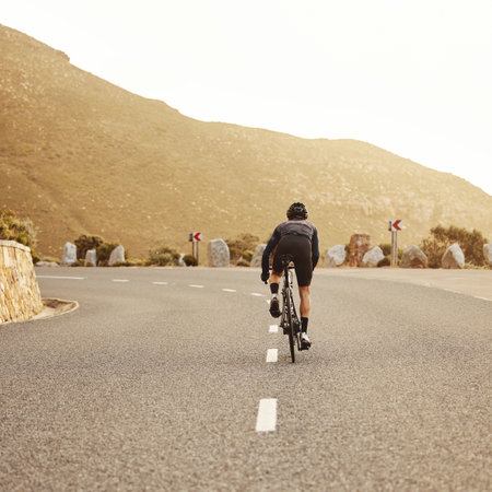 Fitness, cycling and sports man on a bicycle at sunset with mountain view in South Africa, exercise, freedom and health. .Road, cyclist and marathon training by athletic male on morning cardio rideの写真素材