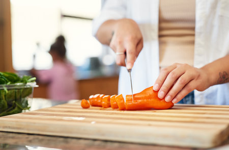 Just add some carrots. a woman chopping carrots at home.の写真素材