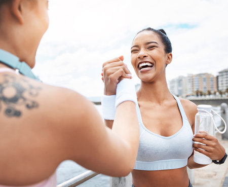 Handshake, women and fitness training winner achievement for running competition in city street. Happy girls, smiling and support after successful sports goal wellness workout together outdoorsの写真素材
