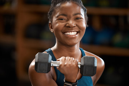 I was born to lift. Cropped portrait of an attractive and athletic young woman working out with a dumbbell in the gym.の写真素材