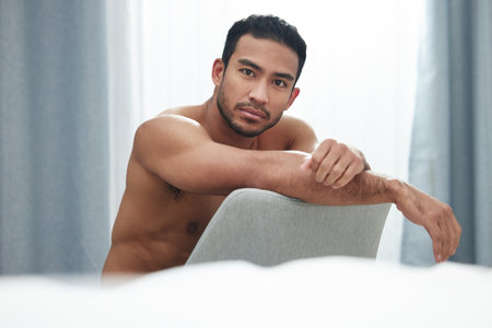 Remember my name and the lectures I bring. Portrait of a handsome young man sitting on a chair after a shower at home.の写真素材
