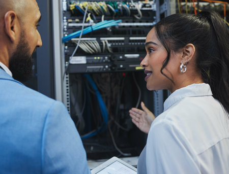 Do we understand each other. two workers inspecting the electronic equipment in a server room together at work.の写真素材