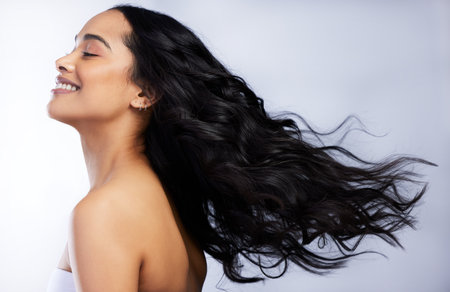 Making the most out of perfectly styled hair. an attractive young woman standing alone in the studio and flipping her hair.の写真素材