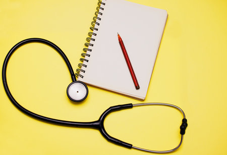 All a doctor needs to make a diagnosis. Studio shot of a stethoscope and a notebook against a yellow background.の写真素材