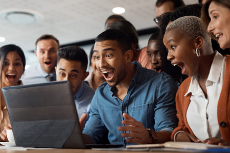Work hard, win big. a group of young businesspeople using a laptop and looking shocked in a modern office.の写真素材
