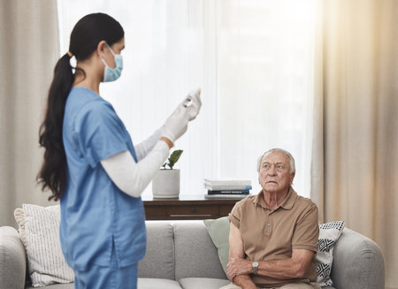 Preparing to get a life changing vaccine. a young female nurse giving an elderly man the vaccine at home.の写真素材