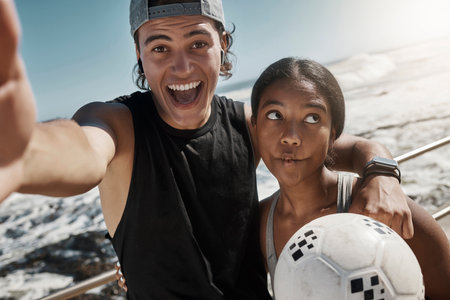 Soccer ball, couple and fun sports selfie by beach, sea or ocean after fitness, workout and training. Portrait, smile and happy man and comic woman in photograph pov after football exercise in Brazilの写真素材