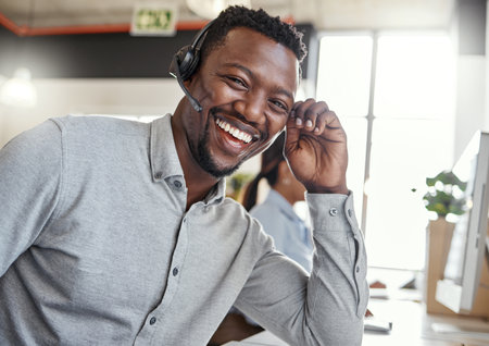 Give me a target and Ill exceed it every time. Portrait of a young man using a headset in a modern office.の写真素材