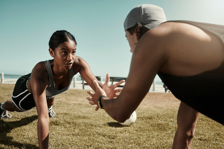Fitness, workout and plank exercise of couple training cardio in a beach park together. Focus, motivation and teamwork or collaboration of a healthy sport athlete and trainer on grass in summerの写真素材