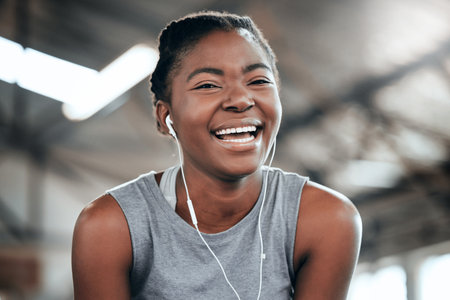 Stayed for the laughs. Portrait of a happy woman using earphones at the gym.の写真素材