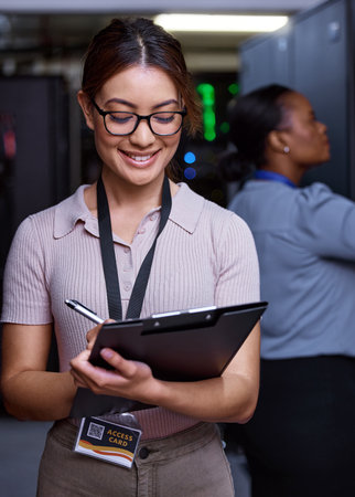 Server maintenance in progress. an attractive young female programmer working in a server room with her colleague in the background.の写真素材
